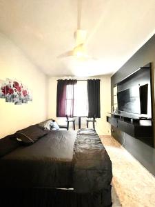 ein Schlafzimmer mit großem Bett und Flachbildfernseher in der Unterkunft Aconchego no Litoral in Santos