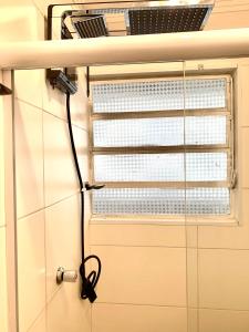 ein Fenster mit einem Schlauch, der an einer Wand hängt in der Unterkunft Aconchego no Litoral in Santos