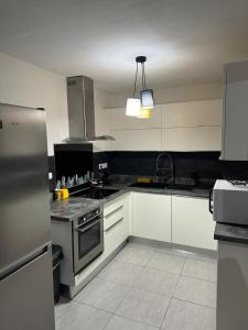 a kitchen with white cabinets and a stainless steel refrigerator at L'ile aux couleurs in Les Abymes
