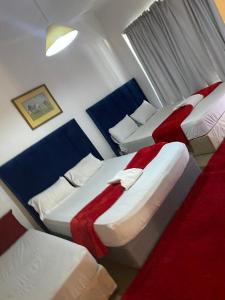 two beds in a room with red and white sheets at two lovers in Vosburg