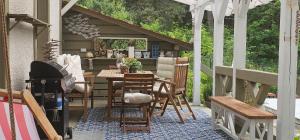 eine Terrasse mit einem Tisch, Stühlen und einem Grill in der Unterkunft Cottage on the Hill in Kielno