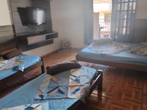 a room with three beds and a flat screen tv at Pousada San Valen in Aparecida