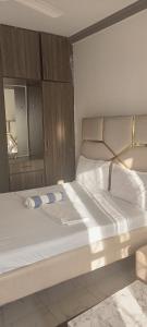 a bedroom with a large white bed with a wooden headboard at Jnjzhomes Mombasa in Mombasa