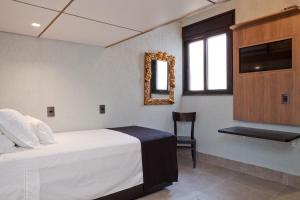 1 dormitorio con cama, espejo y silla en LOFT LAPA Baldô, en Río de Janeiro