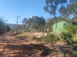 a dirt road with a green building and trees at Pesqueiro Miko-in Rio Aquidauana in Aquidauana