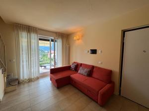 a living room with a red couch in front of a window at Duplex with terrace , pool, 2 bedrooms in Lenno