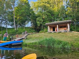 a cabin on the shore of a lake with a boat at Sodyba Voverynė 