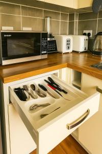 a kitchen with a microwave and a drawer with knives at Rosengelyn Apartment in Sheffield