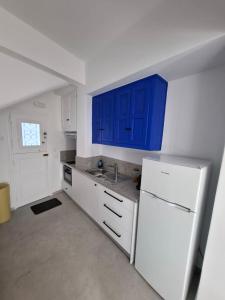 a kitchen with blue cabinets and a white refrigerator at Gazia Sea View House - Mykonos Town in Mikonos +72 photos