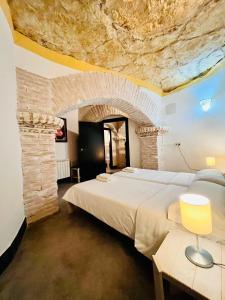 una camera da letto con un letto grande e un muro di pietra di Casa rural cueva El Nido a Casas de los Teatinos