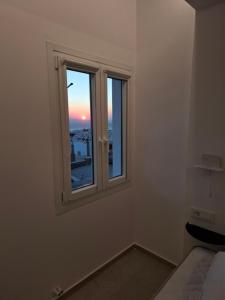 a room with a window with a view of the sunset at Gazia Sea View House - Mykonos Town in Mikonos