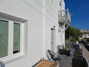 a white building with chairs and a balcony at Gazia Sea View House - Mykonos Town in Mikonos