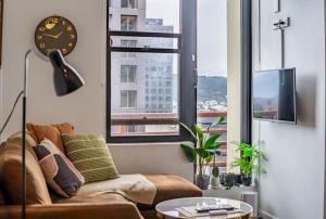 a living room with a couch and a clock at Top Floor - Free Parking - Central Location - Quiet - City View in Wellington