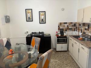 a small kitchen with a glass table and a sink at The Little Blue House in Guayama
