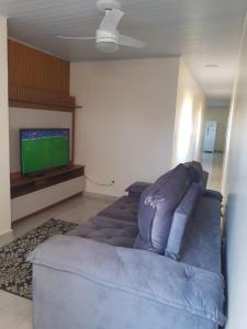 a living room with a blue couch and a tv at Apartamento mobiliado in Itabuna