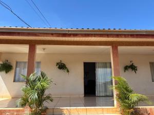 a house with a front door and palm trees at Casa Grande, 3 quartos in Juína