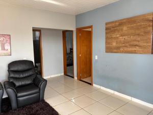 a living room with a chair and a mirror at Casa Grande, 3 quartos in Juína