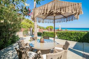 a patio with a table and chairs under an umbrella at Royal Sea View Villa in Vasilikos