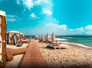 una spiaggia con sedie e ombrelloni e l'oceano di vice city beach resort otel a Arpaçbahşiş