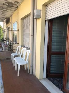 a row of white chairs sitting on the side of a building at Casa Santa Maria Maddalena in Ferrara