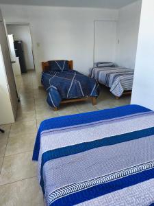 three beds in a room with blue and white at Minidepartamento en el centro de Tacna in Tacna