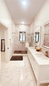 a white bathroom with two sinks and a shower at Blanco Oasis in Banks