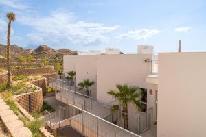 a white building with palm trees and mountains in the background at La Vila - Bolnou Seaviews in Villajoyosa