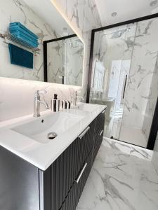 a white bathroom with a sink and a shower at Luxe Capitole122m2, Jacuzzi, Ciné, Parking, Clim, Ascenseur in Toulouse +20 photos