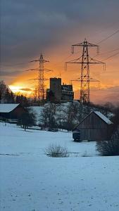 a snowy field with electricity pylons and a building at WS Ferienwohnung in Wolfurt