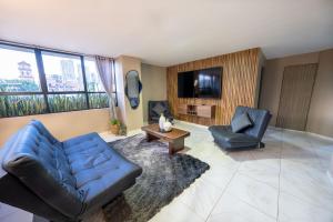 a living room with two blue chairs and a tv at 3 bedroom apartment, with arcade machine - 1 block from lleras park p7 in Medellín