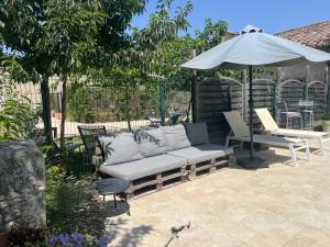 a couch and an umbrella on a patio at Au mas des glycines - Gîte La tropézienne - 5 personnes in Camaret-sur-Aigues