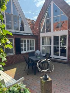 a patio with a table and chairs in front of a house at Das Atelier in Krummhörn