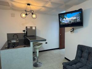 a room with a tv on the wall and a chair at Apartamentos FM 212 in Líbano
