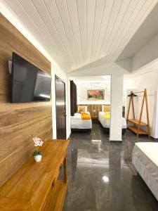 a living room with two beds and a tv on a wall at Pousada Gente Bonita João Fernandes in Búzios