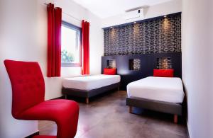 a bedroom with two beds and a red chair at Couleurs K'fé in Saint-Pierre