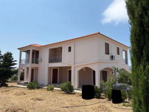 a large white house with trees in front of it at Βίλα Αντί Ονείρου-Διαμέρισμα Αμαλία in Kriezá