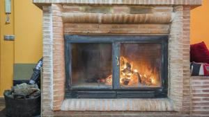 a brick fireplace with a fire in it at Casa Flor de La Jara - An elegant rural retreat in Cobisa