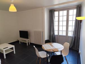 a living room with a table and chairs and a window at O'Couvent - Appartement 301 - 1 chambre - 54 m2 in Salins-les-Bains