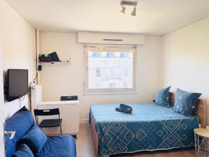 Un dormitorio con una cama azul y un sofá. en Studio pour 2 près de la gare, en Melun