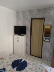 a bedroom with a bed and a television and a door at POUSADA AMAZONAS in Rio das Ostras