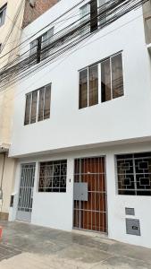 a white building with red doors and windows at WIFI Rápido A 20 min del Aeropuerto de Lima in Lima +8 photos