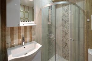 a bathroom with a shower with a sink and a mirror at Aparthotel Paradiso in Nesebar