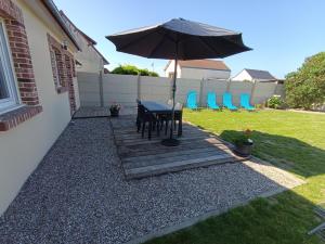 a patio with an umbrella and a table and chairs at Le Nid de la Baie in Pendé