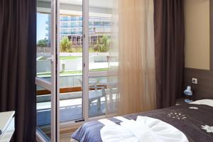 a room with a bed and a balcony with a view at Aparthotel Paradiso in Nesebar