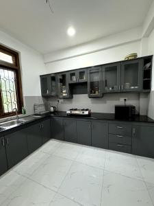 una cucina con armadi neri e pavimento piastrellato bianco di New 3-Bedroom House in Jaffna near Nallur Kovil a Jaffna