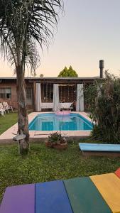 a pool with a palm tree next to a house at Casa en Roldán 2 habitaciones in Roldán