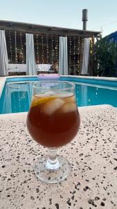 a drink in a glass sitting on a table next to a pool at Casa en Roldán 2 habitaciones in Roldán