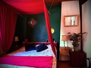 a bedroom with a canopy bed with red curtains at Le petit coin de Paradis in Brissac +4 photos