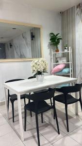 a white table and chairs with a vase of flowers on it at Homestay Tchr azie in Kuantan