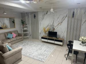 a living room with a television and a marble wall at Homestay Tchr azie in Kuantan